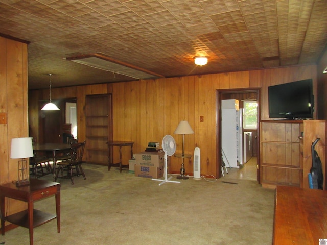 carpeted living room with wood walls and washer / dryer