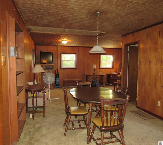 dining space featuring light carpet and wooden walls