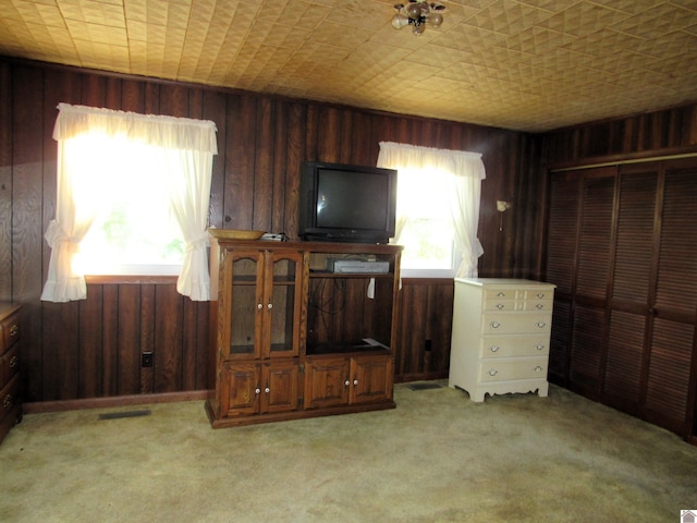 unfurnished living room featuring wooden walls and light carpet