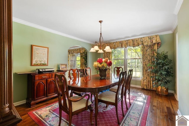 dining room featuring dark wood-type flooring, crown molding, a chandelier, and a wealth of natural light