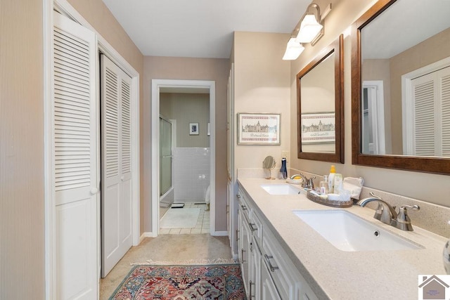 bathroom with a shower with door, tile patterned floors, and vanity