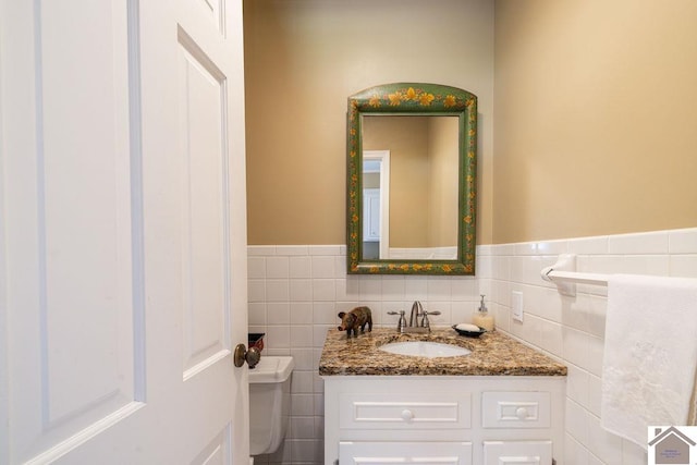 bathroom with vanity, tile walls, and toilet