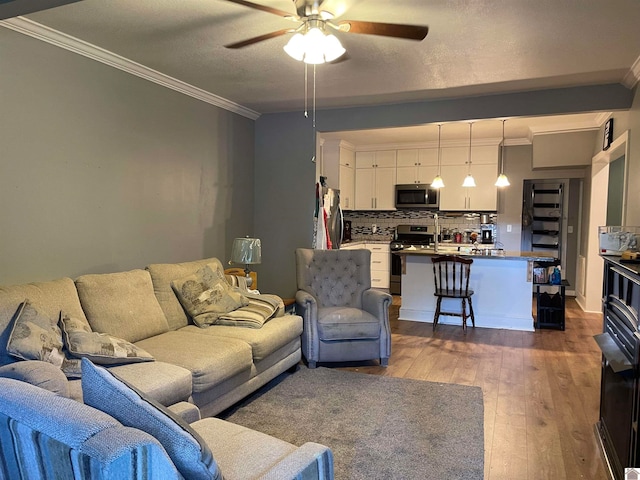 living room with crown molding, ceiling fan, hardwood / wood-style floors, and a textured ceiling