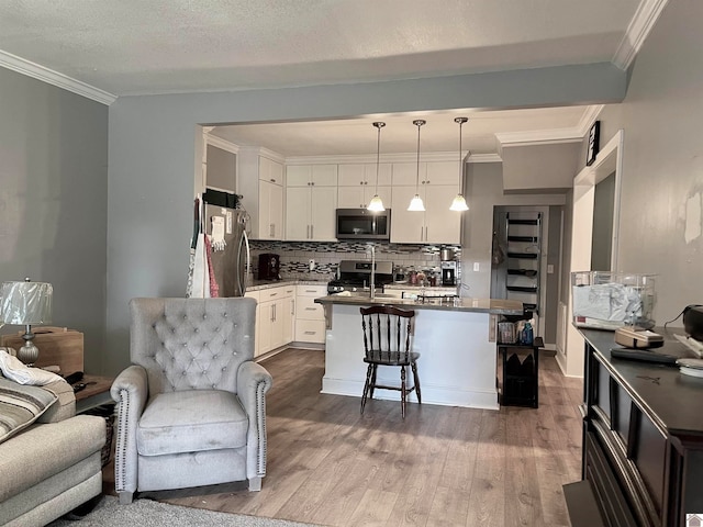 kitchen featuring hardwood / wood-style floors, a breakfast bar, stainless steel appliances, hanging light fixtures, and white cabinets