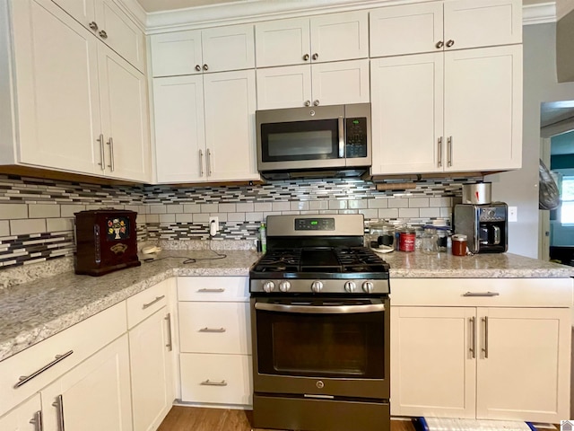 kitchen featuring stainless steel appliances, ornamental molding, white cabinets, and tasteful backsplash