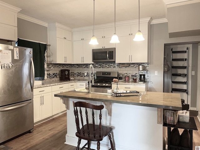 kitchen featuring appliances with stainless steel finishes, dark hardwood / wood-style flooring, a kitchen breakfast bar, and white cabinets