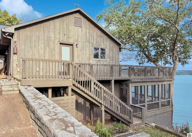 rear view of property with a sunroom and a deck with water view