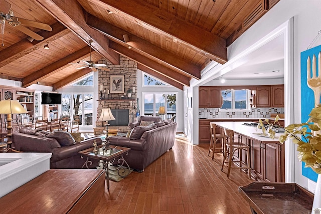 living room featuring a fireplace, wooden ceiling, beam ceiling, and light hardwood / wood-style flooring