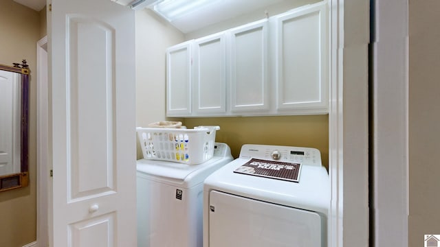 clothes washing area featuring washing machine and dryer and cabinets