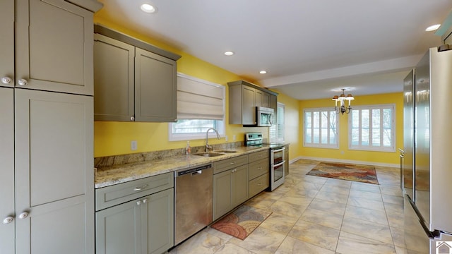 kitchen featuring light stone counters, sink, gray cabinetry, stainless steel appliances, and an inviting chandelier