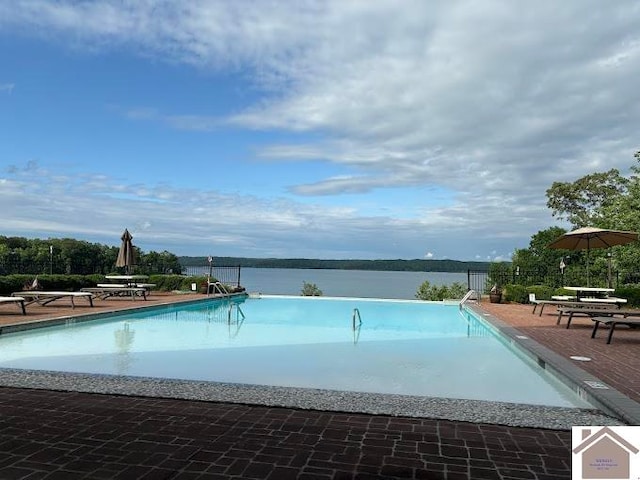 view of swimming pool featuring a water view and a patio area