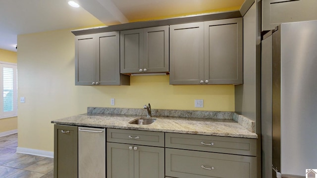 kitchen featuring light stone countertops, gray cabinets, and sink