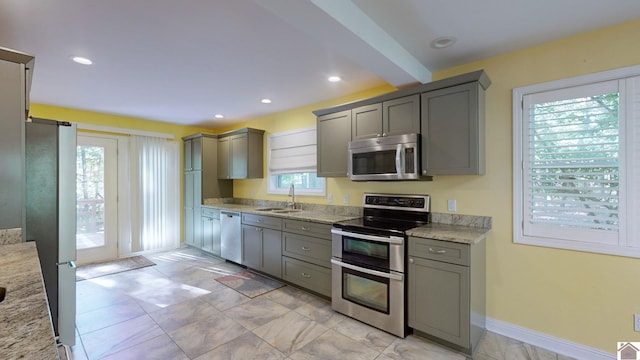 kitchen with appliances with stainless steel finishes, light stone counters, and a wealth of natural light