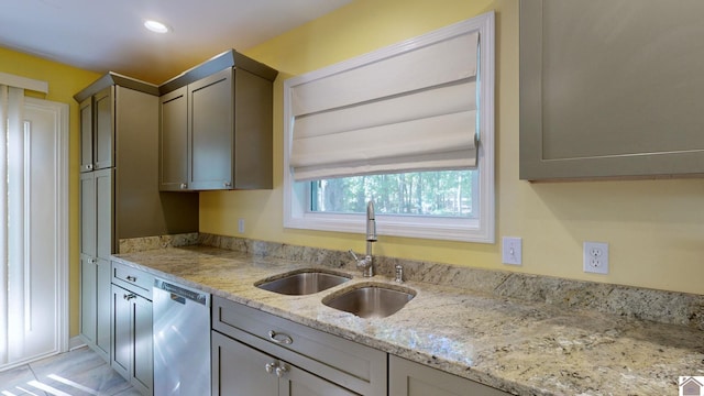 kitchen with light stone counters, dishwasher, sink, and gray cabinetry