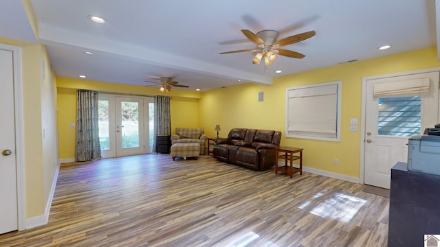 living room featuring wood-type flooring, french doors, beam ceiling, and ceiling fan