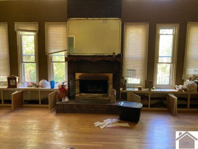 living area with a fireplace, hardwood / wood-style flooring, and a healthy amount of sunlight