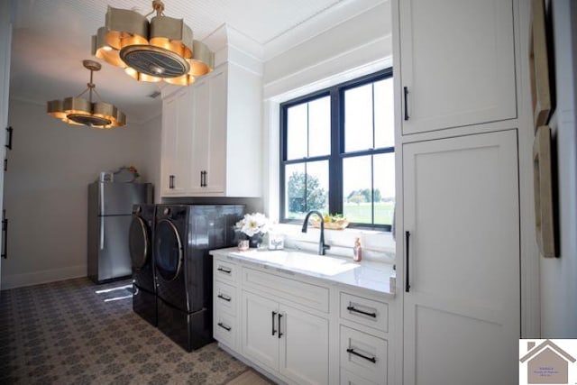 laundry area featuring independent washer and dryer, ornamental molding, cabinets, and sink