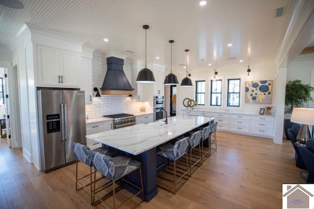 kitchen with appliances with stainless steel finishes, white cabinetry, a breakfast bar, and a spacious island