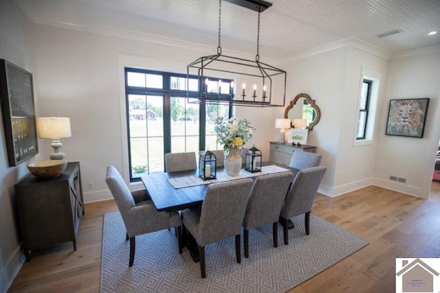 dining area with wood-type flooring, an inviting chandelier, and ornamental molding