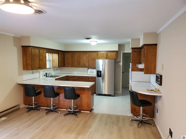 kitchen featuring stainless steel fridge, ornamental molding, kitchen peninsula, a kitchen breakfast bar, and light wood-type flooring