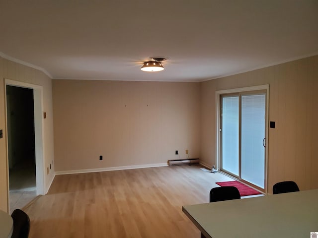 interior space with ornamental molding, light wood-type flooring, and a baseboard heating unit