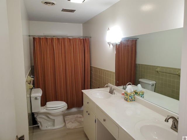 bathroom featuring vanity, tile walls, and toilet