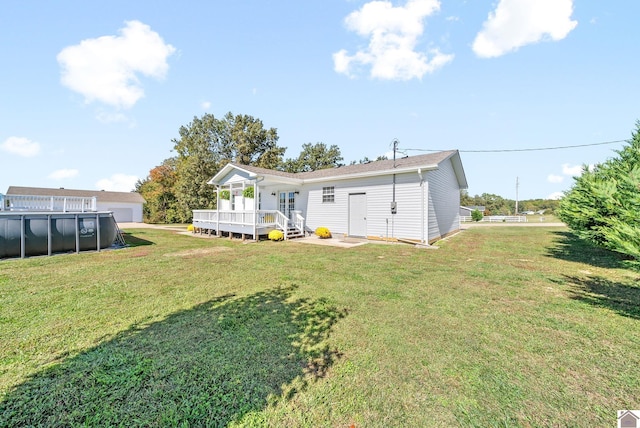 rear view of house featuring a yard and a pool side deck