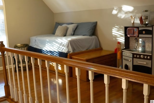 bedroom with vaulted ceiling, hardwood / wood-style flooring, and sink