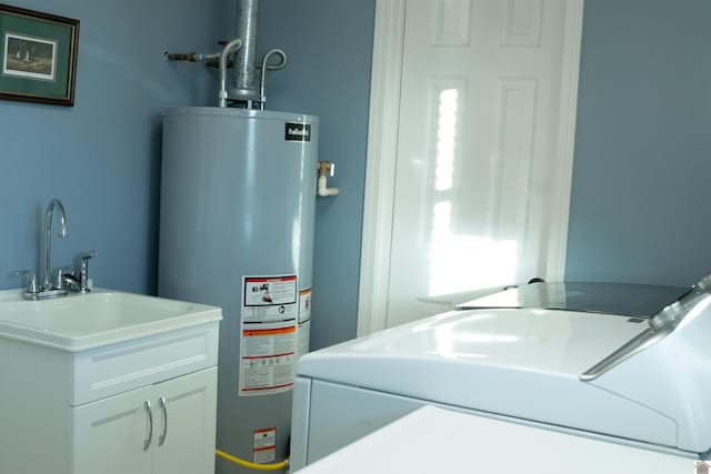 utility room with gas water heater, washer and dryer, and sink