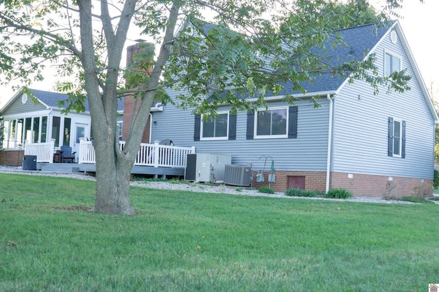 exterior space featuring a wooden deck, a lawn, and central AC unit