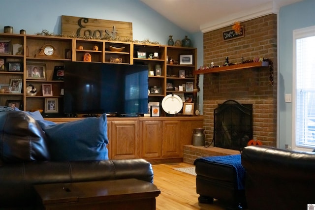 living room featuring a brick fireplace, vaulted ceiling, and light wood-type flooring