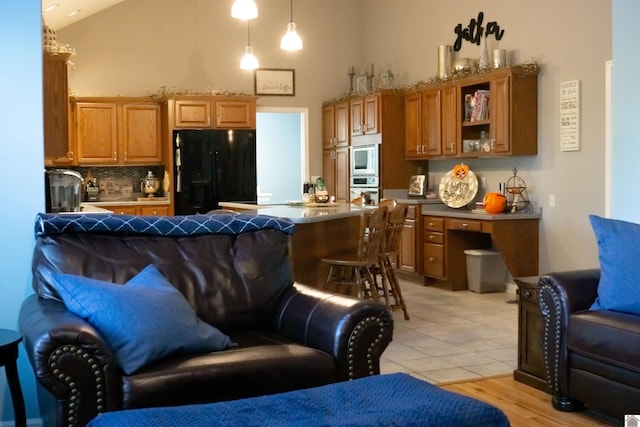 kitchen featuring white microwave, stainless steel oven, decorative backsplash, hanging light fixtures, and black refrigerator