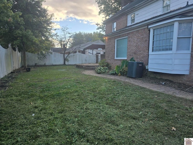 yard at dusk featuring central AC