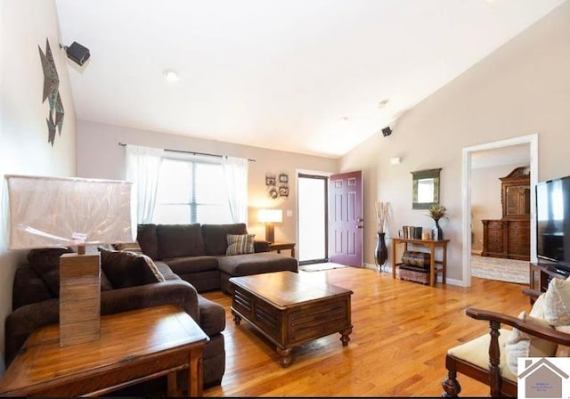 living room featuring light wood-type flooring and high vaulted ceiling