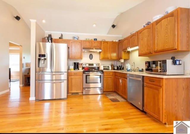 kitchen with sink, stainless steel appliances, light hardwood / wood-style floors, and lofted ceiling