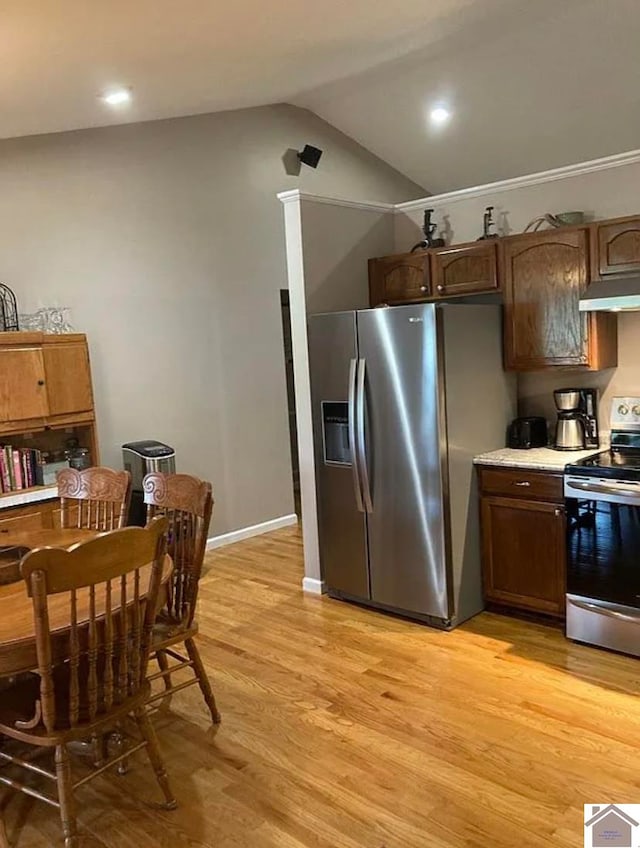 kitchen with stainless steel appliances, light wood-type flooring, and vaulted ceiling