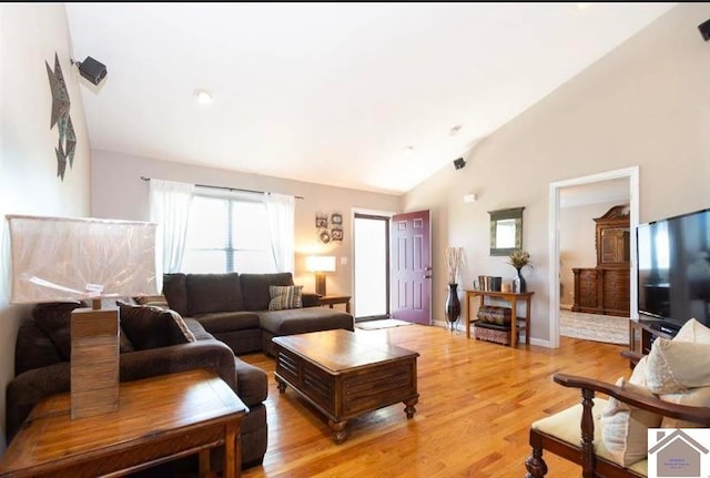 living room featuring high vaulted ceiling and light hardwood / wood-style floors