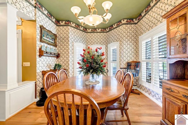 dining area featuring light hardwood / wood-style flooring, a notable chandelier, and decorative columns