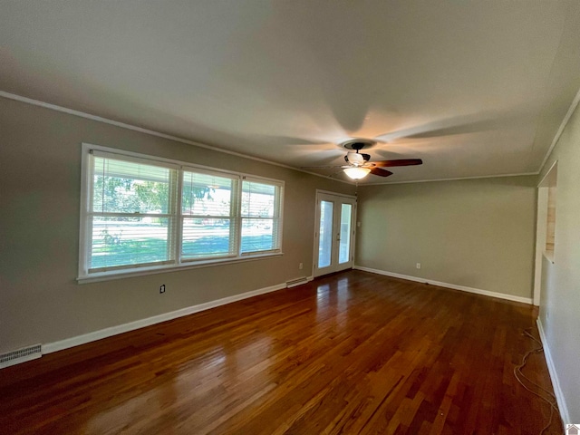 empty room featuring french doors, ornamental molding, dark wood-type flooring, and ceiling fan