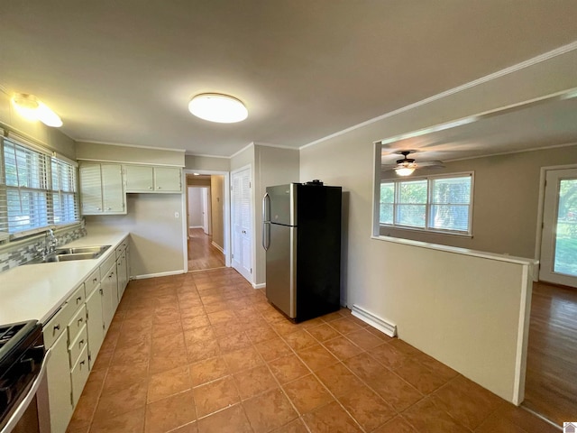 kitchen with ceiling fan, white cabinets, ornamental molding, sink, and stainless steel appliances