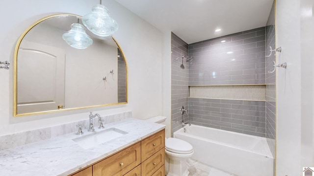 full bathroom featuring tiled shower / bath, vanity, and toilet