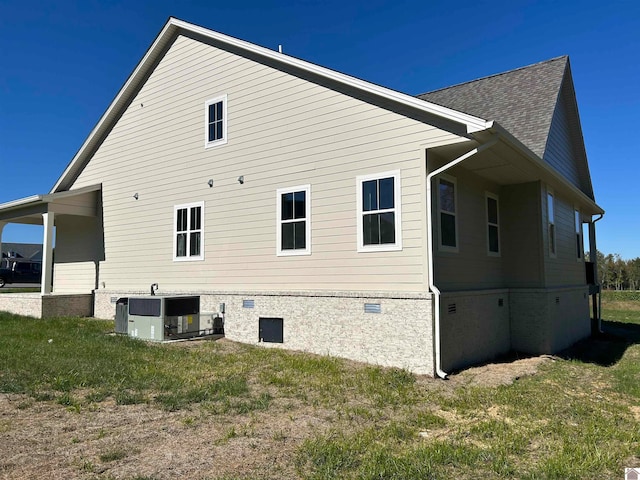 view of side of home with central AC and a yard