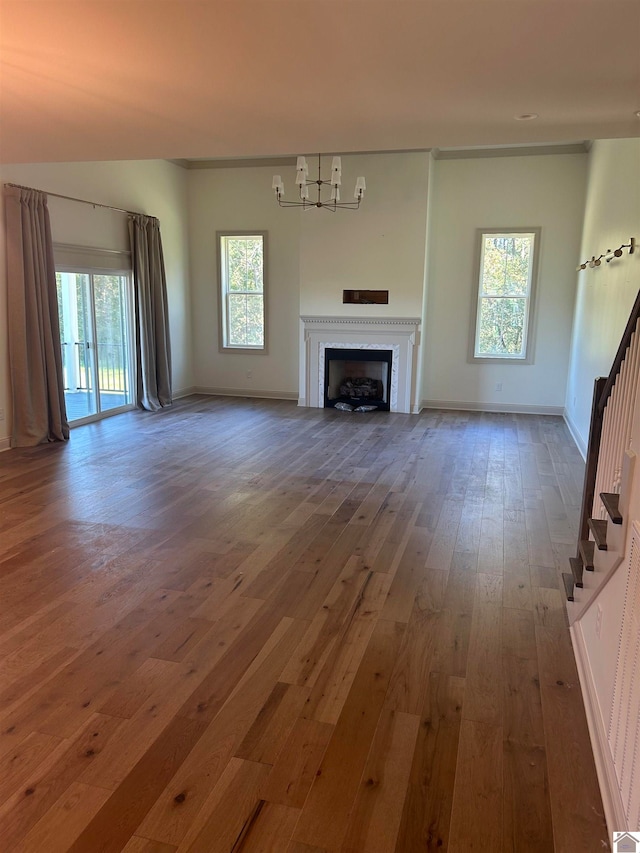 unfurnished living room with a chandelier, dark wood-type flooring, and plenty of natural light