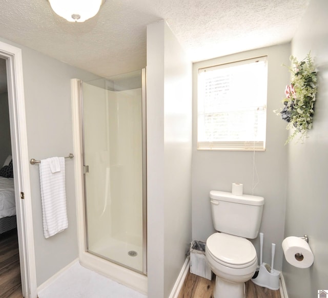 bathroom with a shower with door, toilet, a textured ceiling, and hardwood / wood-style floors