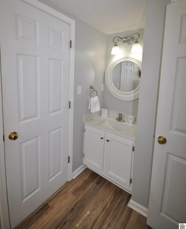 bathroom featuring vanity, wood-type flooring, and a textured ceiling