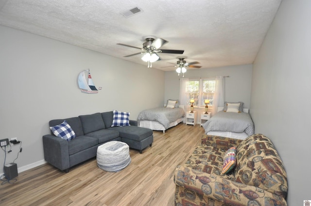 bedroom featuring a textured ceiling, light wood-type flooring, and ceiling fan