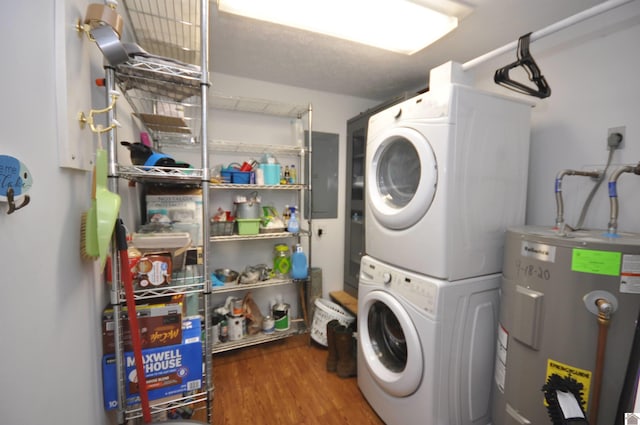 clothes washing area featuring a textured ceiling, water heater, dark wood-type flooring, stacked washing maching and dryer, and electric panel