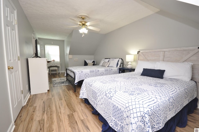 bedroom with a textured ceiling, wood-type flooring, vaulted ceiling, and ceiling fan