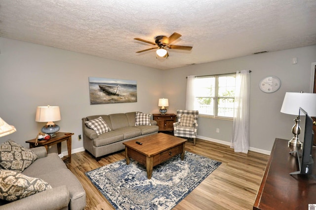 living room with a textured ceiling, light wood-type flooring, and ceiling fan