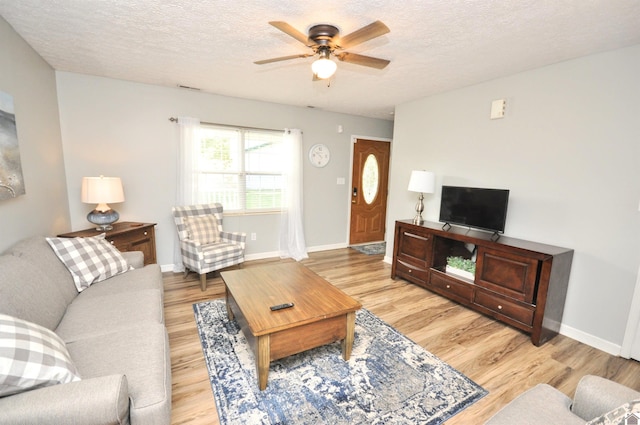 living room with light hardwood / wood-style flooring, a textured ceiling, and ceiling fan